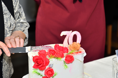 Grandma  cut with a knife with sweet cake to celebrateの写真素材