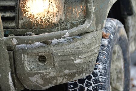 Detail of a dirty wheel, a lit light and a mudguard off-road car in forest