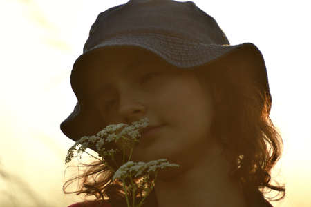 Silhouette of yung girl posing on a meadow in the tall grass at sunset