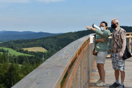 A man and a woman in protective masks and gloves look at the surrounding nature and forestsの写真素材