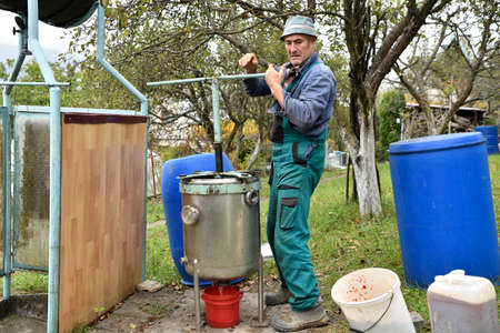 The fruit farmer rotates the press by hand while pressing the apples into fruit must