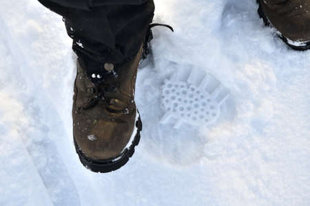 A hiking boot and its imprint in the snow from a tourist's footの写真素材