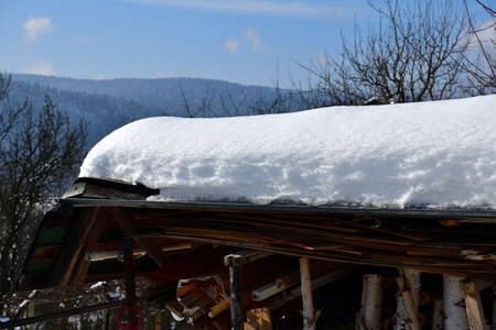 Thick layer of freshly fallen snow on the roofs of houses and cottages in natureの写真素材