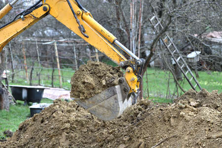 The excavator's shovel picks up the soil while digging on the construction place
