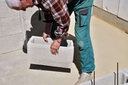 The mason places and prefabricated blocks into the wall at home on the construction site