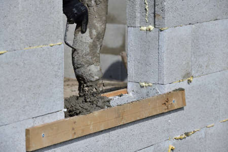 A concrete worker on a construction site concretes walls using a machineの写真素材