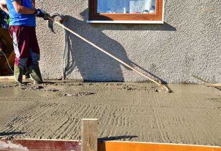 Leveling concrete with a wooden tool on a construction siteの写真素材