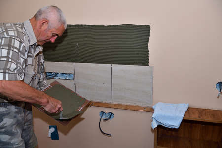 The mason puts tiles on the wall in the kitchenの写真素材