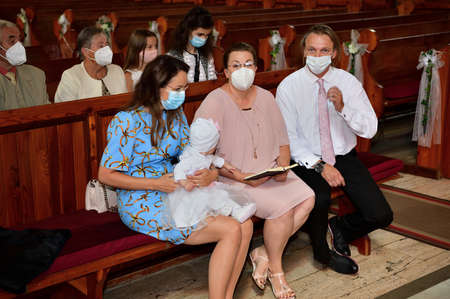 A family sits in a church with protective masks on their faces