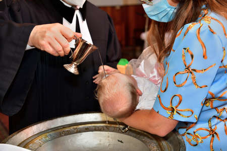 The pastor baptizes a child in the church using holy water