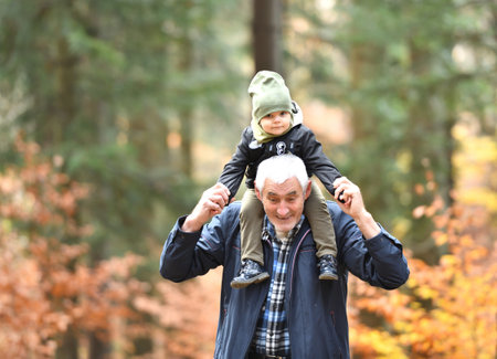 Facial expressions of a little girl who is carried on her grandfather's shoulders during a walk in...