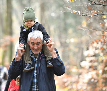 Facial expressions of a little girl who is carried on her grandfather's shoulders during a walk in...