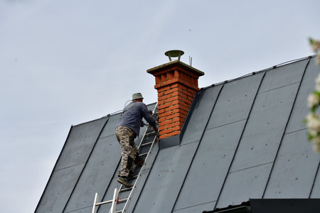 A  chimneyer climbs a ladder to the roof to repair a chimneyの写真素材
