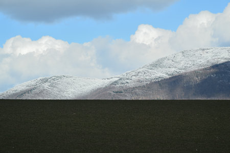 Blue sky with white clouds over mountain peaks at the end of winterの写真素材