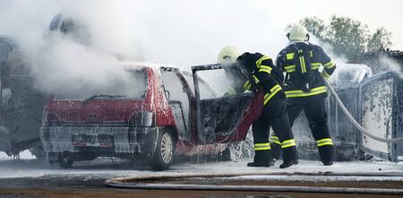 Fireman fighting a car fire after a road accident 