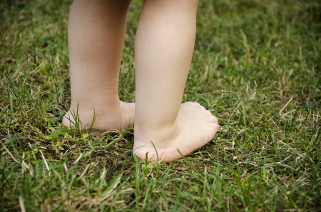 Little baby child feet standing on a green grass.の写真素材
