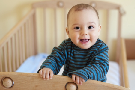 Baby with a cute happy face standing in a cot.の写真素材
