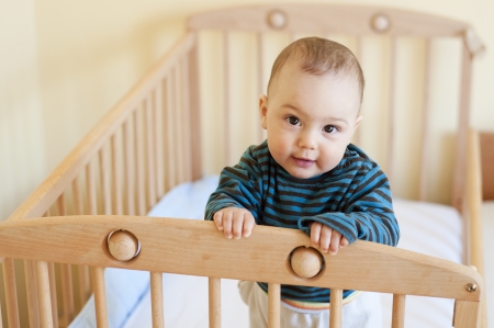 Baby with a cute happy face standing in a cot.の写真素材