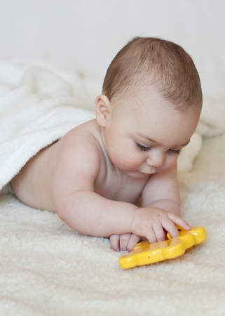 Baby lying on her belly  playing with a plastic toyの写真素材