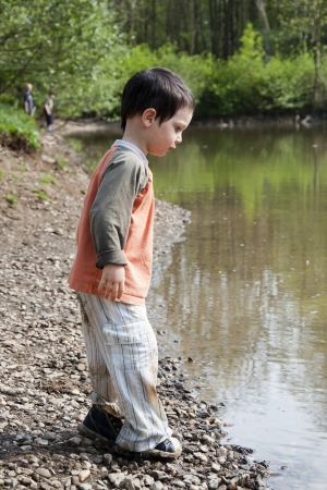 Children playing  on the edge of the lake or a river in the nature.の写真素材