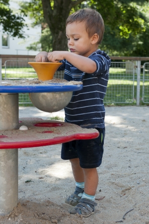 Child playing with sand at playground on a play table equipment  の写真素材