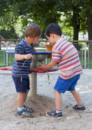 Children playing with sand at playground on a play table equipment の写真素材