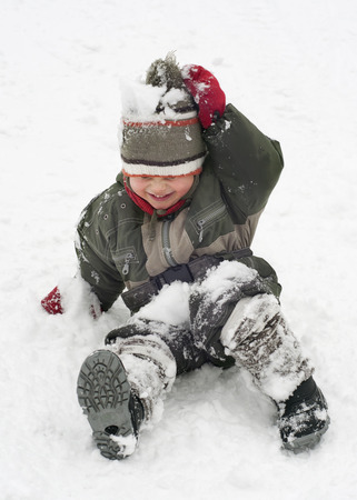 Happy chiild toddler, boy or girl, in snow licking  his cold hands  in winter  の写真素材