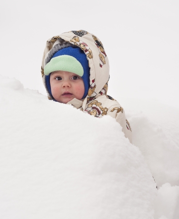 Baby child in fresh deep snow in winter. の写真素材
