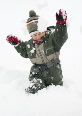 Happy chiild toddler, boy or girl, in snow licking  his cold hands  in winter. の写真素材