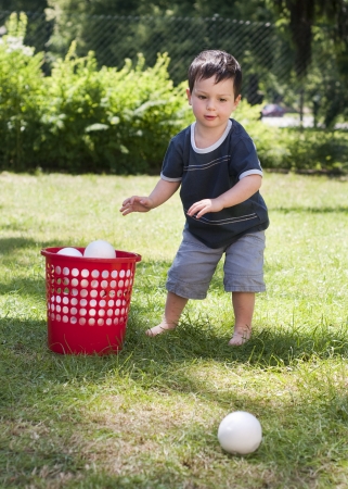 A child boy playing with a small  balls on a grass in the garden の写真素材