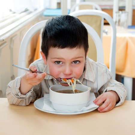 Small child boy eating a soup in a restaurant.の写真素材