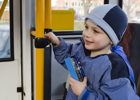 Child travelling on publec bus, holding a toy bus in his hand  の写真素材