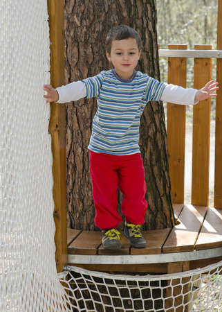 Portrait of a child boy climbing into a net at aventure playground.の写真素材
