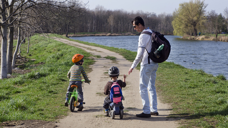 Father with children on a cycling path along a river. の写真素材