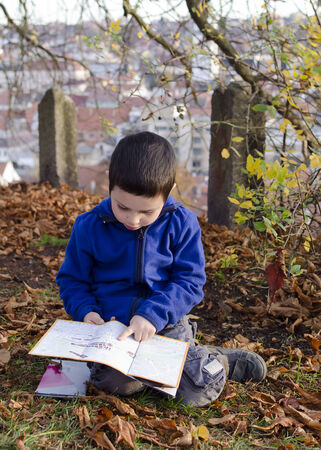 Child boy reading a map or city plan while sitting on groundの写真素材