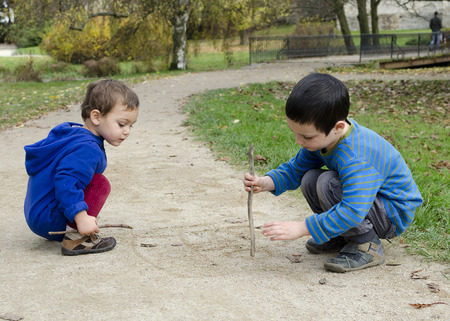 Children draw into sand on a path in parkの写真素材