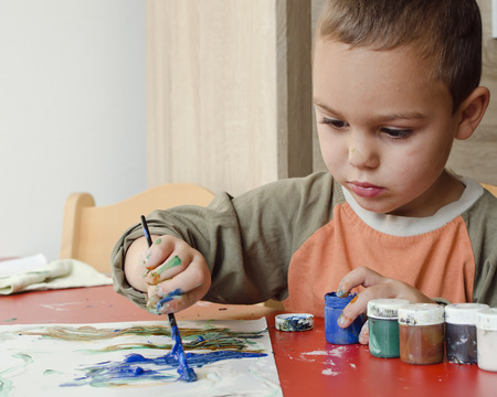 Child boy painting a picture with brush at home or school nursery.の写真素材