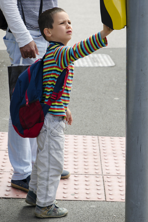 School child boy pressing a button on pedestrian road crossing.の写真素材