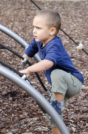 Child playing at children playground, climbing the  rope frame.の写真素材