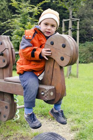 Child playing in a playground in a park swinging on a wooden seesaw.の写真素材