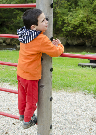 Child playing on a climbing frame at children playground at park.の写真素材