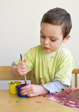 Child boy painting a picture with brush at home or school nursery.の写真素材