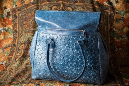 blue leather vintage bag on background with flowers and abstract patterns, blue vintage leather bag front view, blue ladies leather bag, blue womens leather bagの写真素材