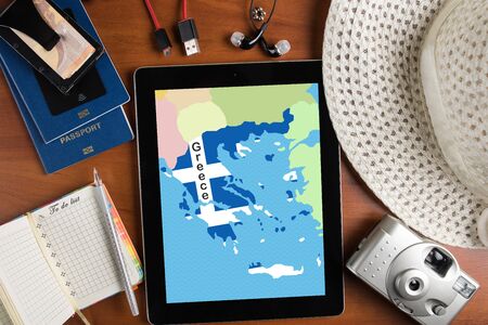 overhead view of traveler's accessories and map of Greece on tablet, travel concept background, map of Greece on tablet display and essential vacation items, passports, notepad and tourist country mapの写真素材
