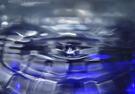 Shiny drop on the water surface in blue color.の写真素材