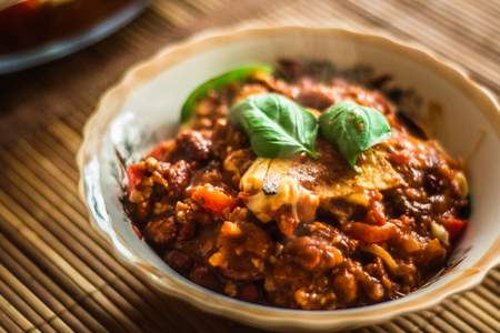 Food chili con carne with fresh basil and nachos, located on a bamboo matの写真素材