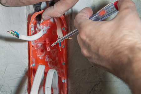 Hands with electrical tester checking the voltage of electrical cablesの写真素材