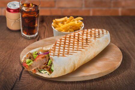 Gyros pita sandwich with french fries and cola on wooden background. For fast food restaurant design or fast food menuの写真素材
