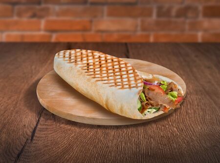 Pita wrap sandwich on wooden background. For fast food restaurant design or fast food menuの写真素材