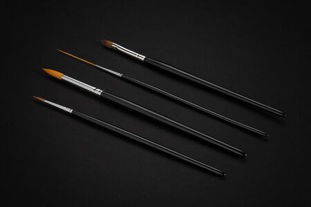Set of cosmetic brushes, different forms. On black background. Top view. Cosmetics and beauty concept. Copy spaceの写真素材